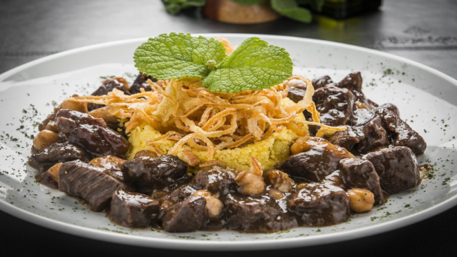 Maktube com couscous marroquino e cebola crocante, servido com couscous marroquino e cebola crocante. Prato principal do almoço e jantar do Almakan Gastronomia Árabe.