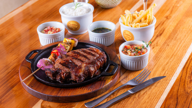 Bife chorizo assado na parrilla argentina, com arroz branco, batatas, vinagrete e chimichurri, do Churrasco ao Vivo.
