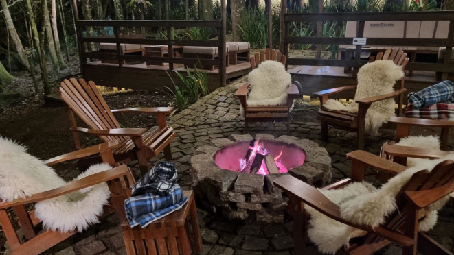 Área externa do restaurante Maria Eugênia, com lareiras, cobertores e pelegos, em volta do fogo.