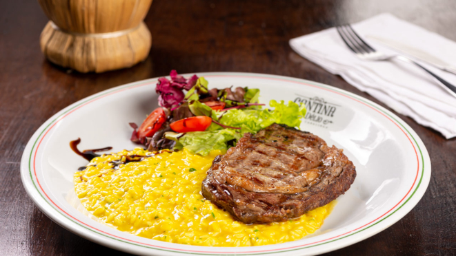 No almoço, o prato principal é contrafilé grelhado servido com risoto, parmesão e manteiga. A Cantina do Délio também tem outras opções com carne no menu.