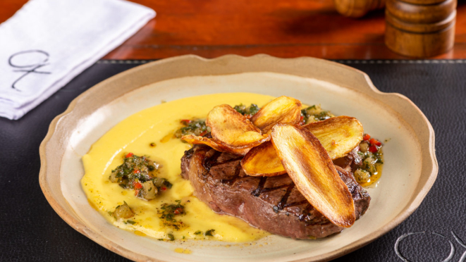 No almoço, o prato principal é um ribeye grelhado com batata salsa e chimichurri de abacaxi. No jantar, também traz outras opções com carne.