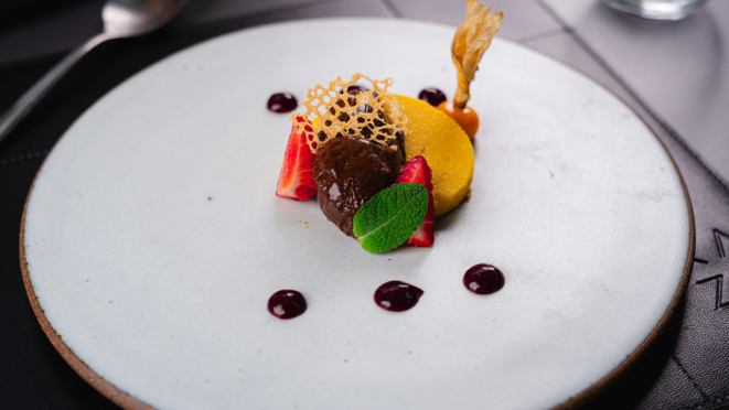 Cheesecake de cabotiá servida com calda de frutas vermelhas e mousse de chocolate belga no Emy by KAZUO.