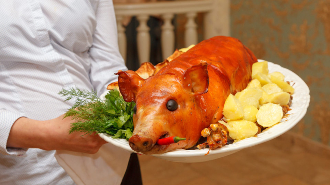 A figura do leitão inteiro colocado sobre a mesa traz a ideia da abundância para a ceia.| Foto: Bigstock
