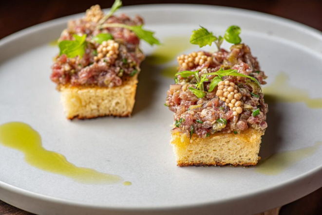 Steak tartar de carne de sol em pão brioche, tostado na manteiga de garrafa e com picles de mostarda. | Foto: Gaby Schroeder