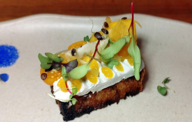 Brioche na brasa, creme de queijo de cabra, frutas amarelas, tomate verde fermentado e maionese de fermento. | Foto: Anacreon de Téos