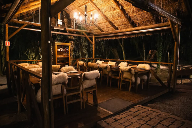 Uma das cabanas cobertas do Restaurante Maria Eugênia, debaixo das árvores, com todo conforto para as noites de inverno. | Foto: Kauana Bechtloff