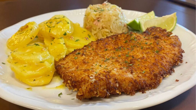 O tradicional Schnitzel alemão do Die Oma: lombo de porco empanado servido com limão, acompanhado de chucrute e salada de batata. Crédito: Divulgação.