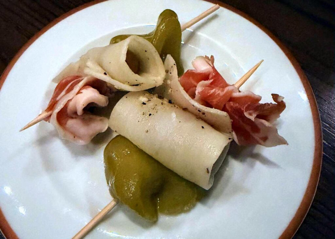 Gilda, um pintxo com picles de pimenta cambuci e uva verde, palmito pupunha e jamón no palito.