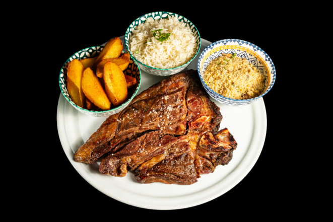 O <em>T-Bone steak Black Angus</em> (filé mignon e contrafilé no mesmo osso, grelhado na busca da perfeição, acompanhado de arroz branco, batata rústica crocante e a farofa de bacon tostada) | Foto: Divulgação