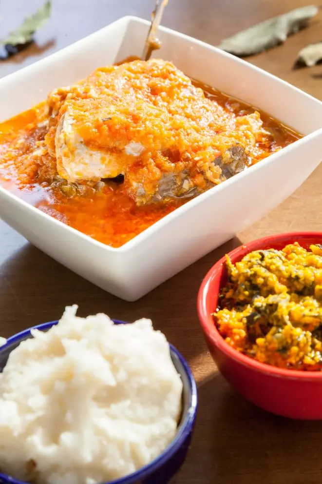 Sopa de peixe com fufu (no potinho à direita) e molho de egusi e espinafre. Foto: Fernando Zequinão / Gazeta do Povo.<br>