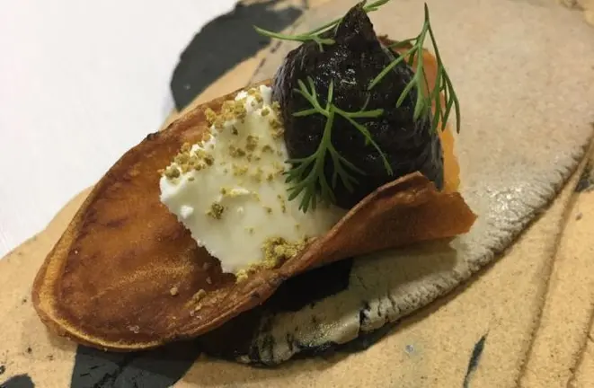 Snack de berinjela com queijo fresco de cabra, pólen de uruçu amarela e mel de saiqui fermentado de 6 a 8 meses. Foto: Manu Buffara/Divulgação