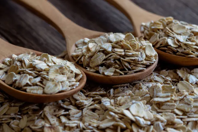 Oat flakes or oatmeal in wood spoon on rustic wood table. Rolled oat is clean food for health lover people. Prepare oat flakes for bakery or cooking.Natural organic food in vintage style concept.Oat flake, oatmeal background and texture.