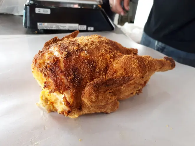 O frango é empanado na farinha de fubá e assado por três horas. Foto: Guilherme Grandi/Gazeta do Povo.
