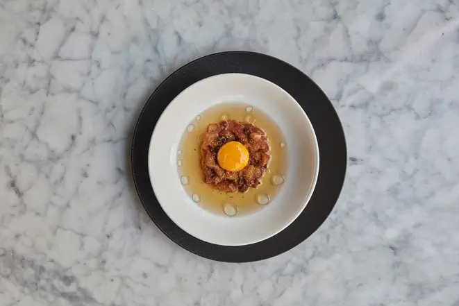 Tartar de pescado, caldo de carne e gema de ovo, prato do restaurante Ambrosía. Foto: Divulgação