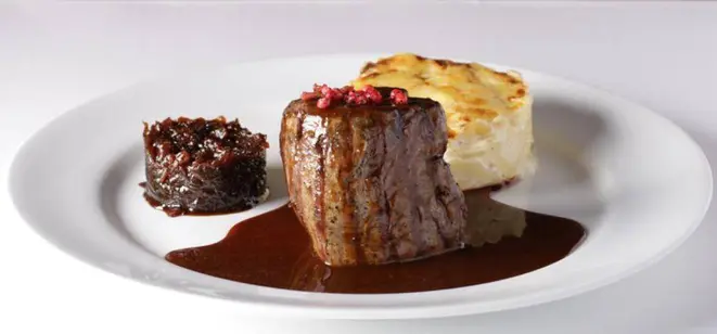 Tournedos de filé mignon ao molho poivre, confit de cebola e batatas gratinadas - o prato principal do L'Épicerie.
