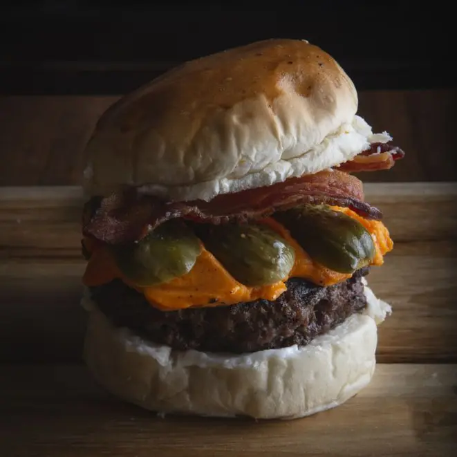 Porks Bacon Burger, preparado com burger de costelinha de porco, creme de cheddar e tiras de bacon crocante, do Porks – Porco & Chope. Foto: Divulgação