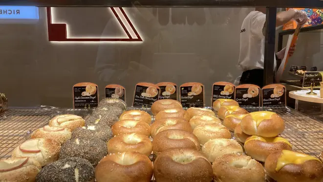 A Terra dos Bagels te convida a passear pela vitrine por um cardápio com 11 bagels com massas, recheios e coberturas que te fazem escolher com a ajuda do unidunitê. Alinhados cuidadosamente parecem desejar pular um a um no seu prato.