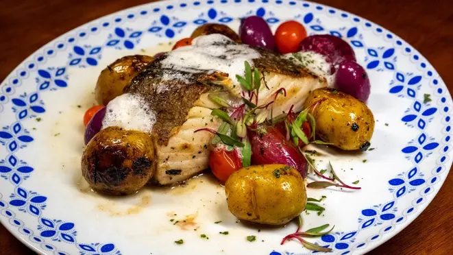 Bacalhau do chef (Gadus morhua) que acompanha batatas, cebolas baby, confit de tomates cereja e azeitonas azapa.