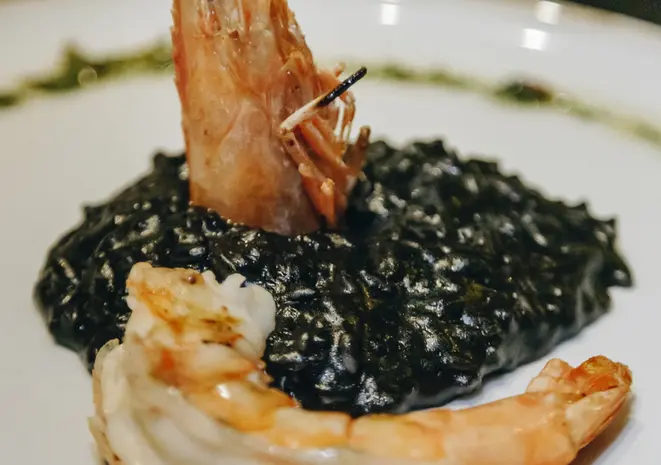 Novidade no cardápio: Camarões na brasa, molho de limão siciliano, servidos com um risoto à nero di sépia (tinta de lula) e tomates assados.