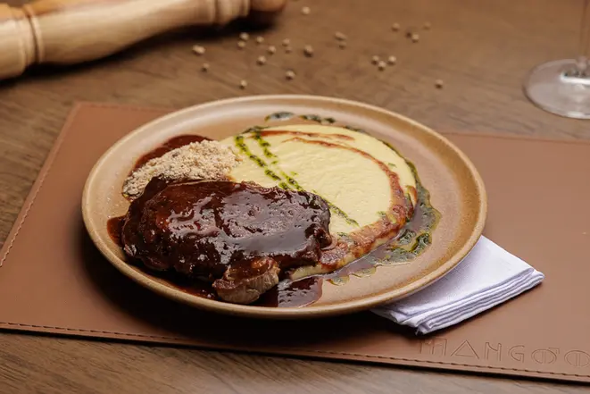 Ancho ao molho demi-glace, com aligot e farofa crocante, no Mangôo.