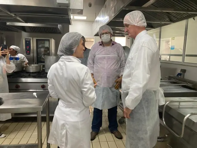 Ana Elisa Elera Negrão (à esquerda) e Fernando César de Oliveira (à direita) com Leonardo Cabral (centro) na cozinha do setor de Nutrição e Dietética do Hospital Erasto Gaertner. Foto: Bom Gourmet