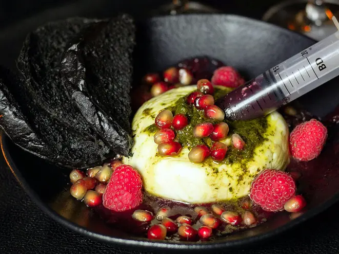 <em>The dark calling</em> combina burrata italiana de leite de vaca, pesto de manjericão, frutas vermelhas e romã, acompanhados de pão brioche negro. | Foto: Bruna Lima